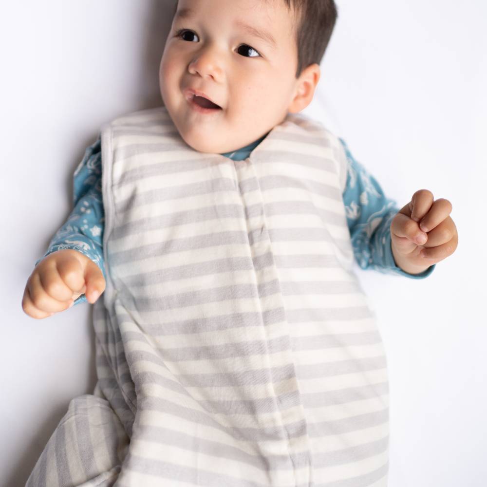 Baby wearing a striped sleeping bag on a plain background