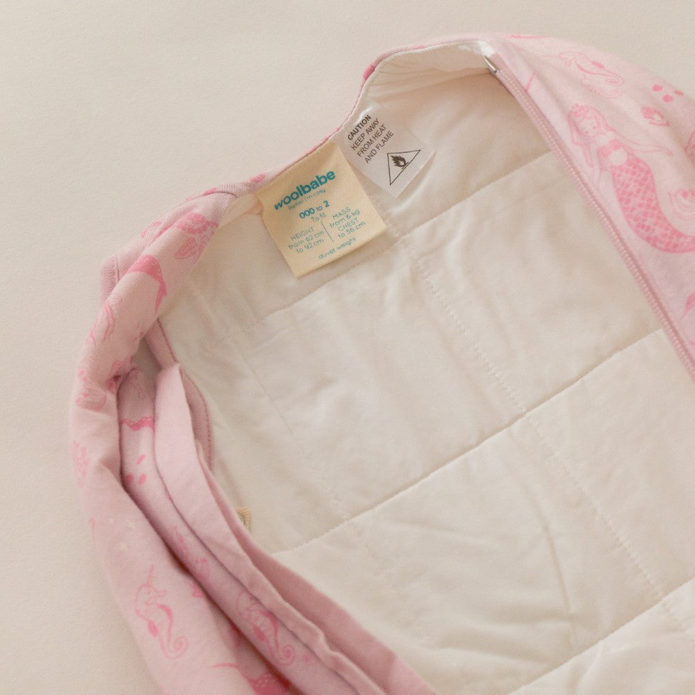 Pink and white quilt with a visible brand tag on a beige background