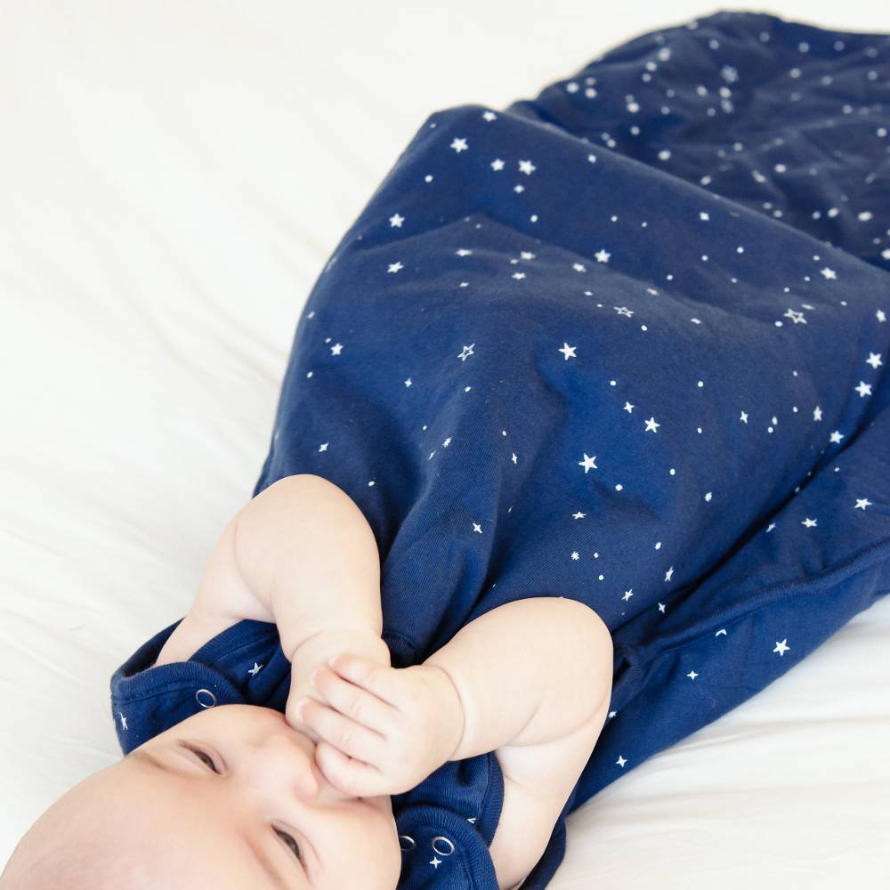 Baby wrapped in a blue blanket with star patterns on a white background