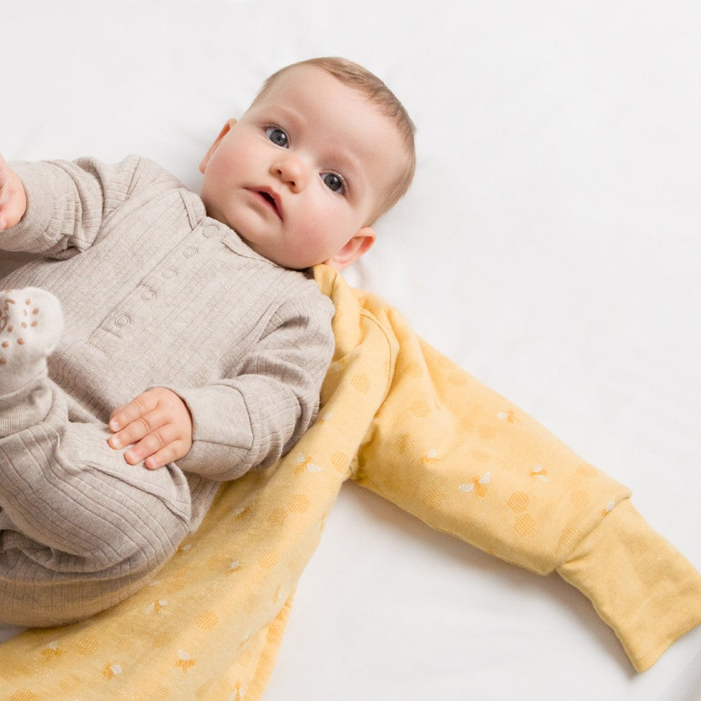 Baby lying on a yellow blanket with a white background