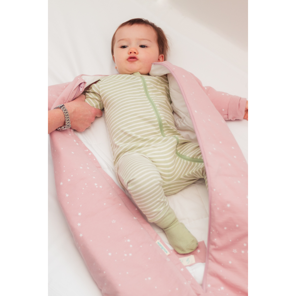 Baby wrapped in a pink and white polka dot swaddle blanket on a white background