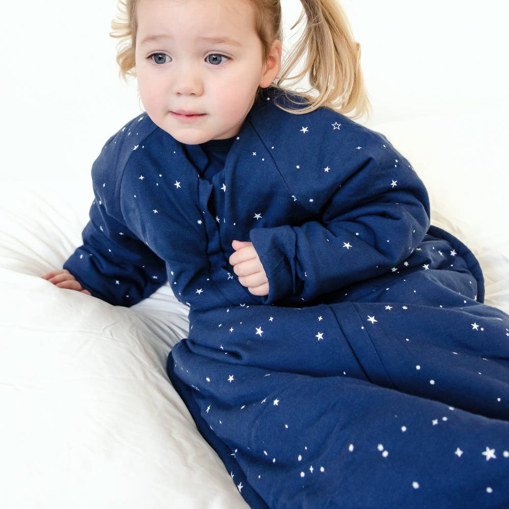 Child wearing a blue onesie with white star patterns on a white background