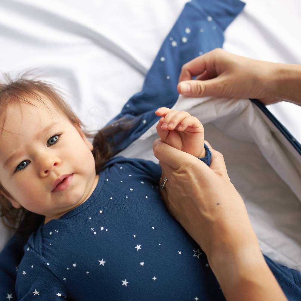 Child wearing a blue shirt with star patterns, lying on a white surface.