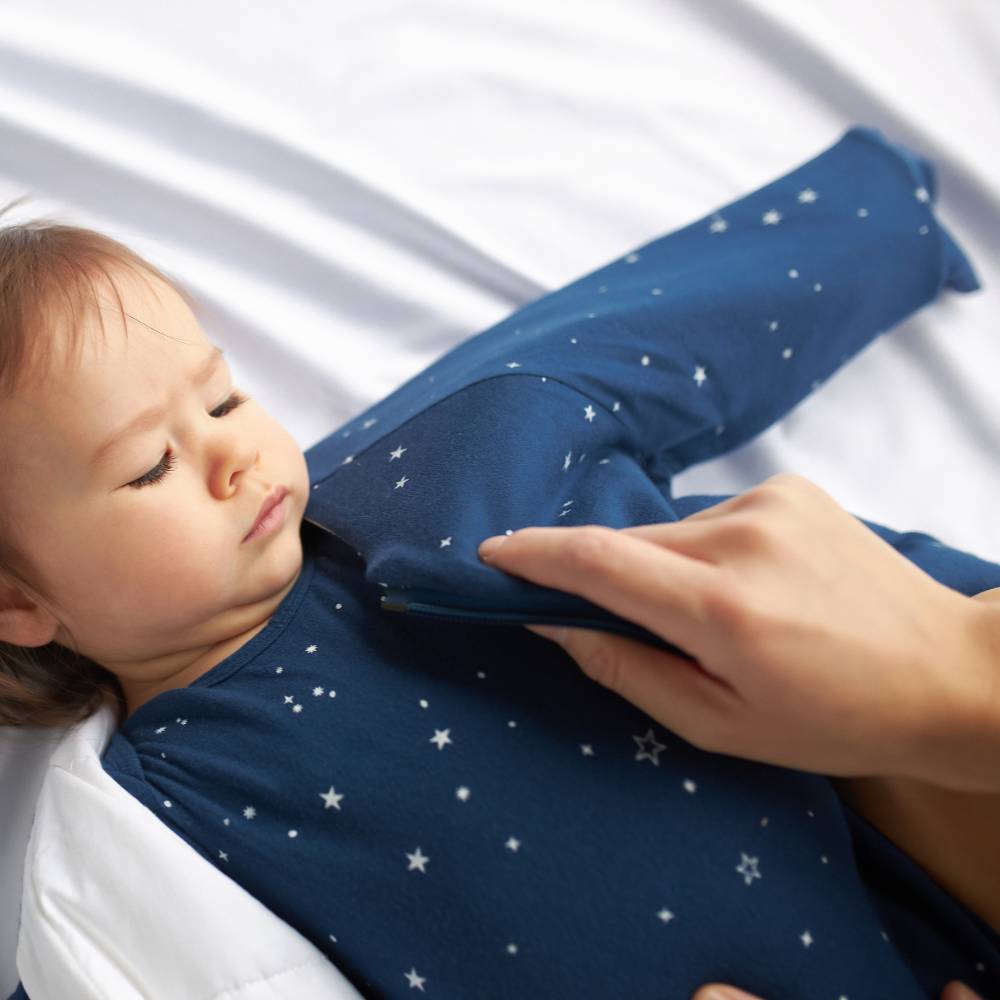 Child wearing a navy blue outfit with star patterns, lying on a white surface.