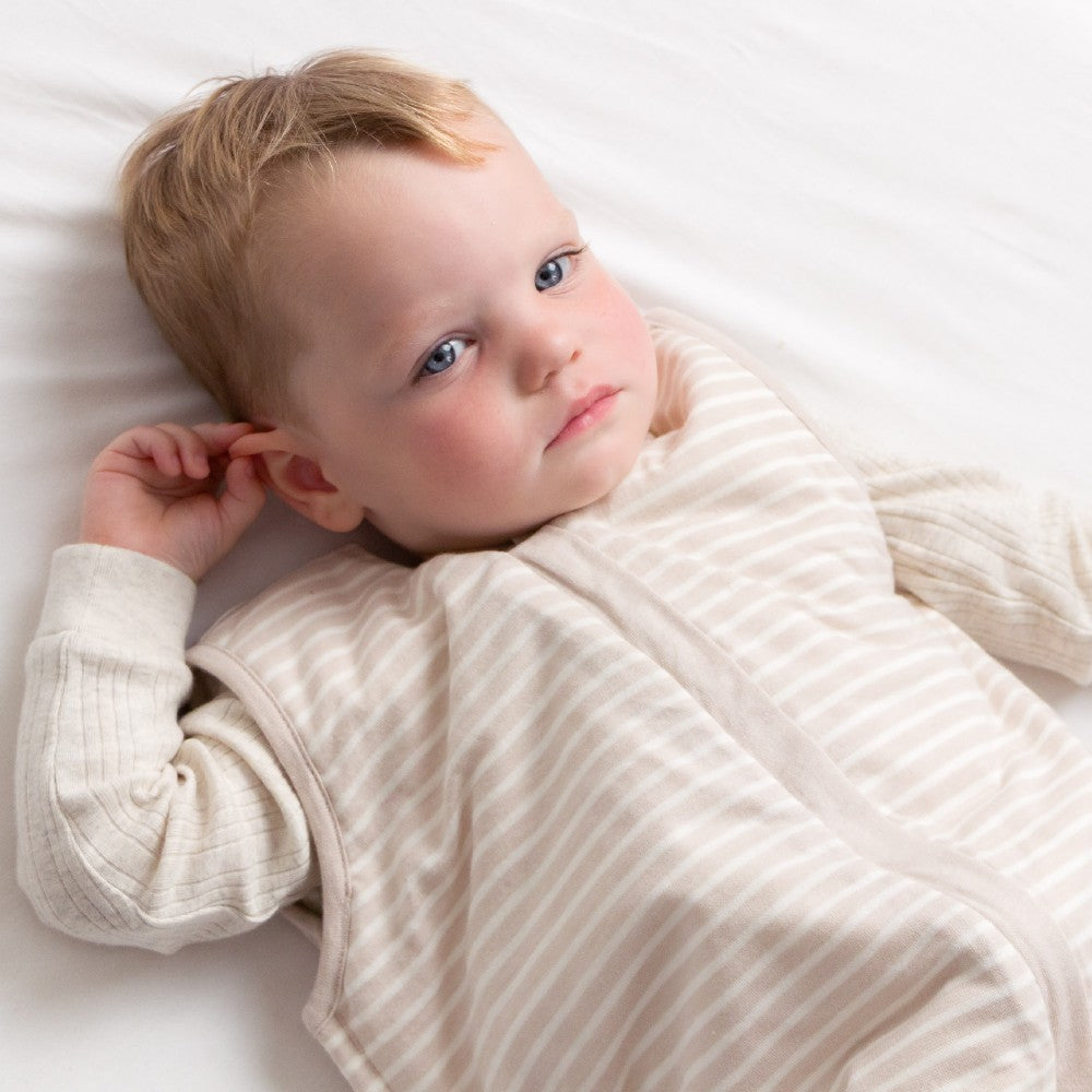 Child wearing a beige sleepsuit on a white background