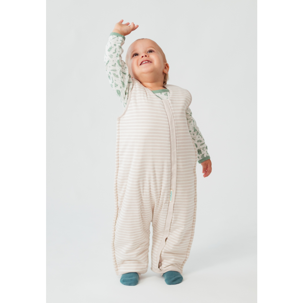 Baby wearing a white onesie with a patterned long-sleeve shirt underneath on a light gray background