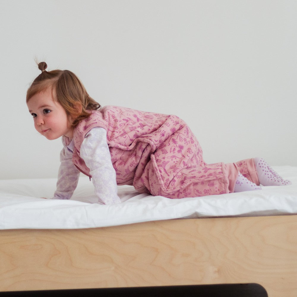 Child in pink sleep onesie on a white surface