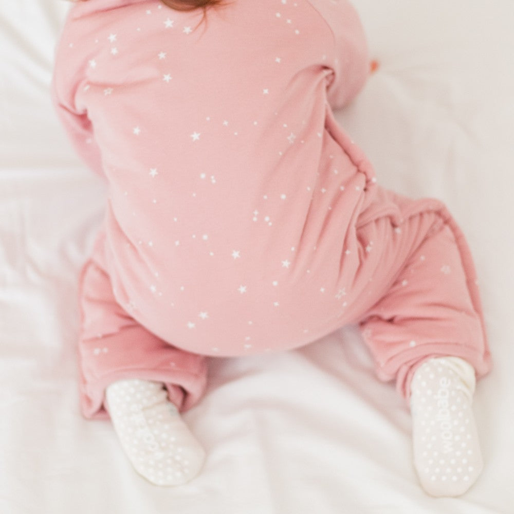 Baby in pink outfit with star pattern lying on a white surface