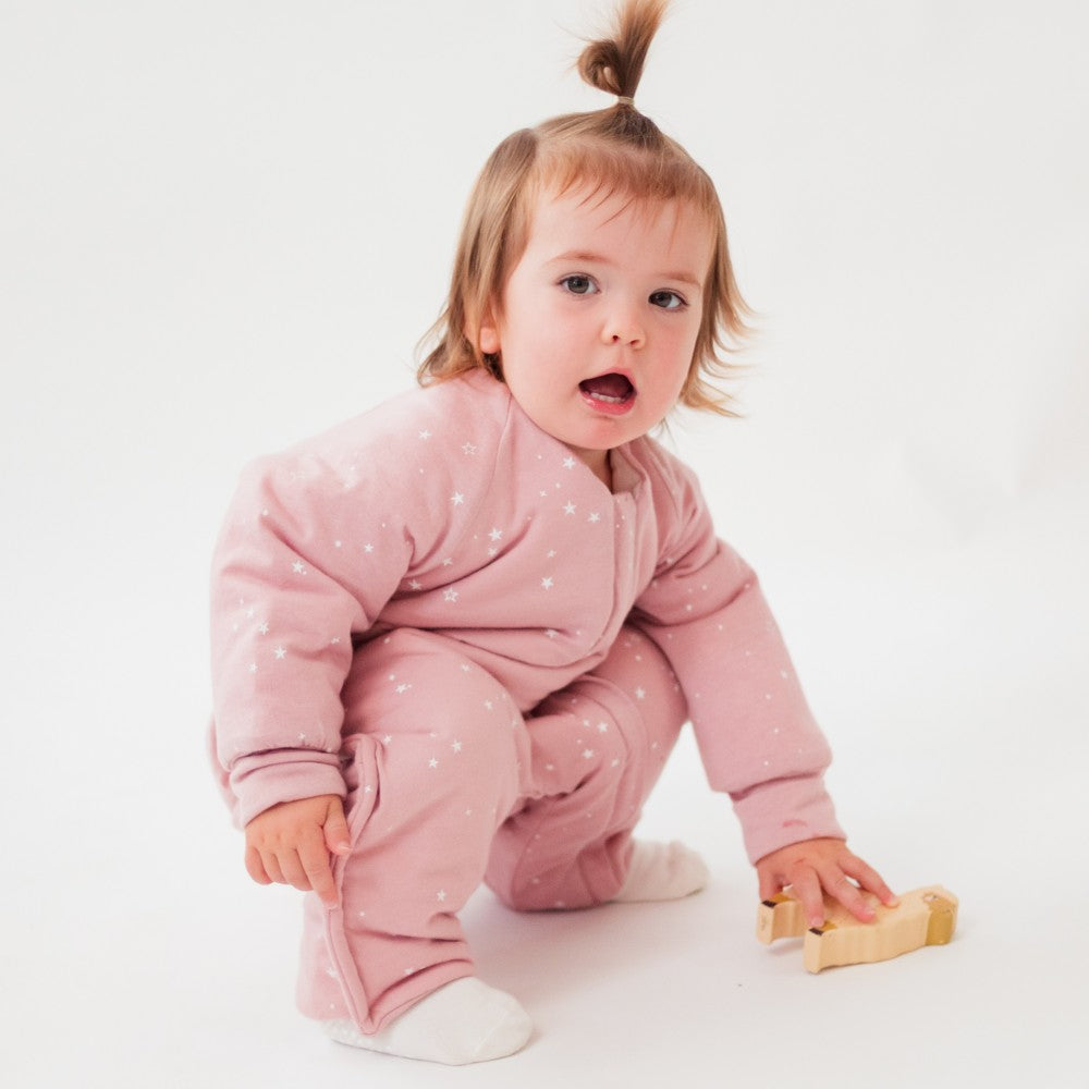 Child wearing a pink merino onesie with white polka dots on a white background