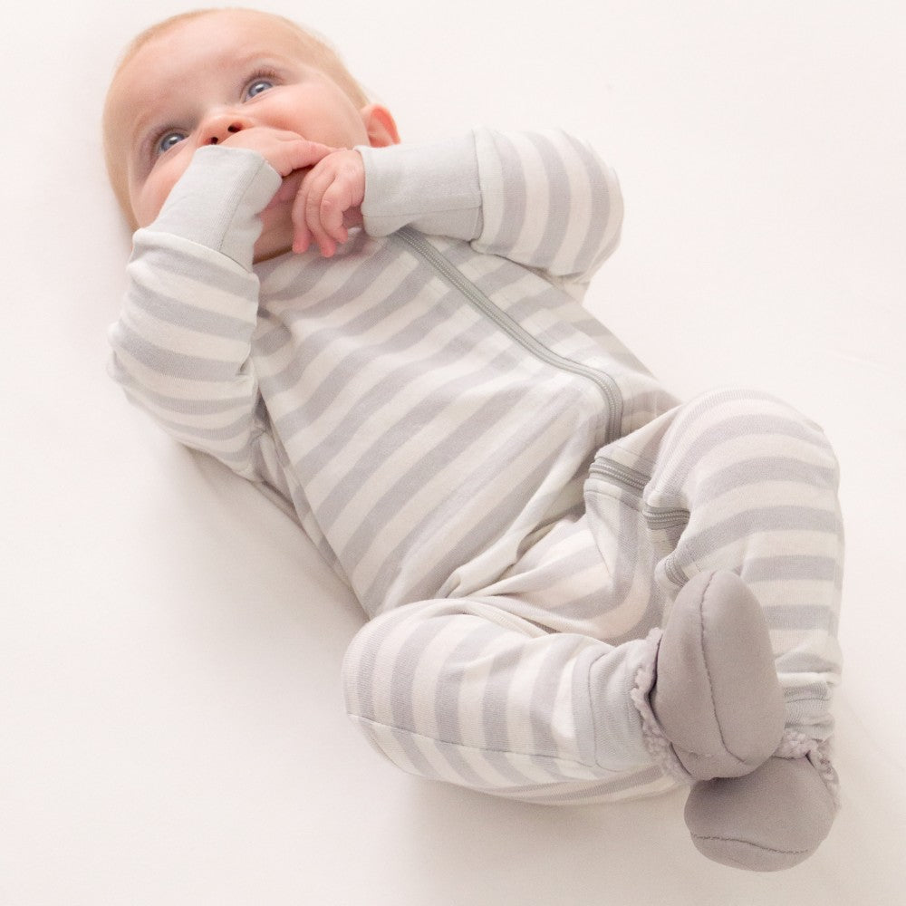 Baby wearing a gray and white striped onesie and grey woolbabe lambskin booties on a white background