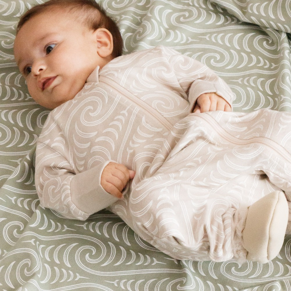 Baby in a patterned outfit lying on a textured surface