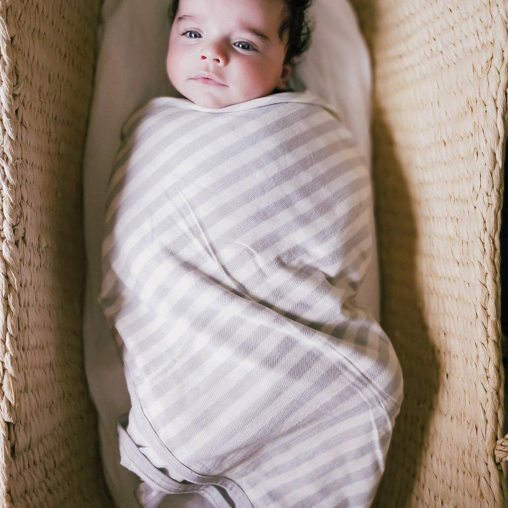 Newborn baby swaddled in a striped blanket inside a woven basket