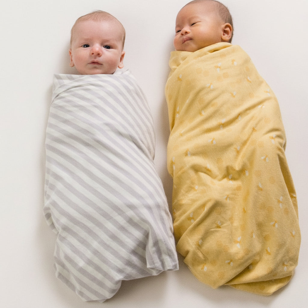 Two babies wrapped in swaddles on a white background
