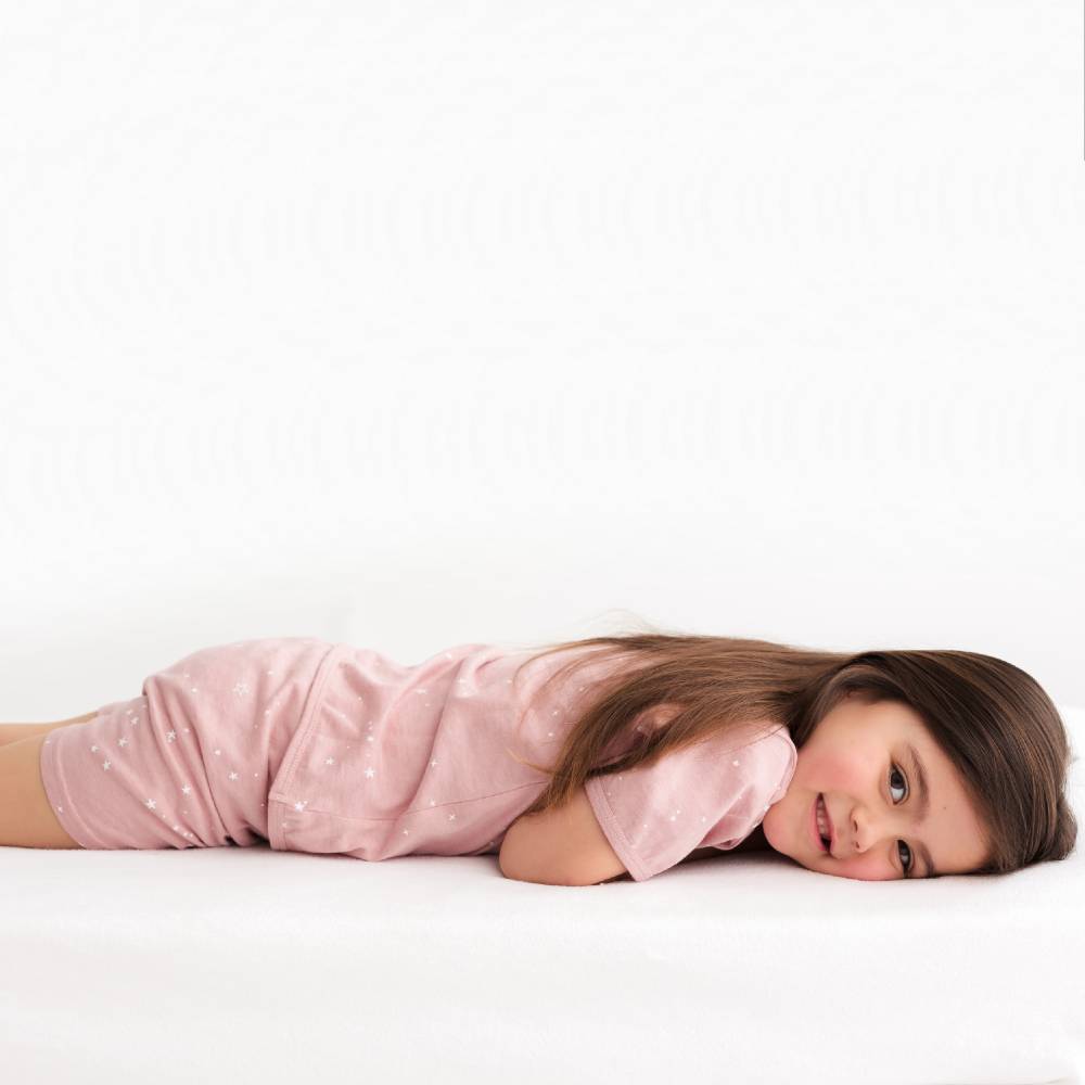 Child wearing a pink polka dot outfit lying on a white background