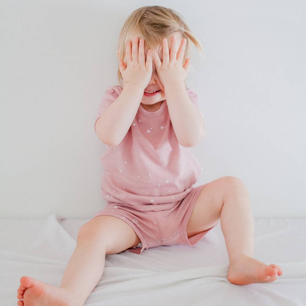 Child wearing a pink outfit with white polka dots on a light background