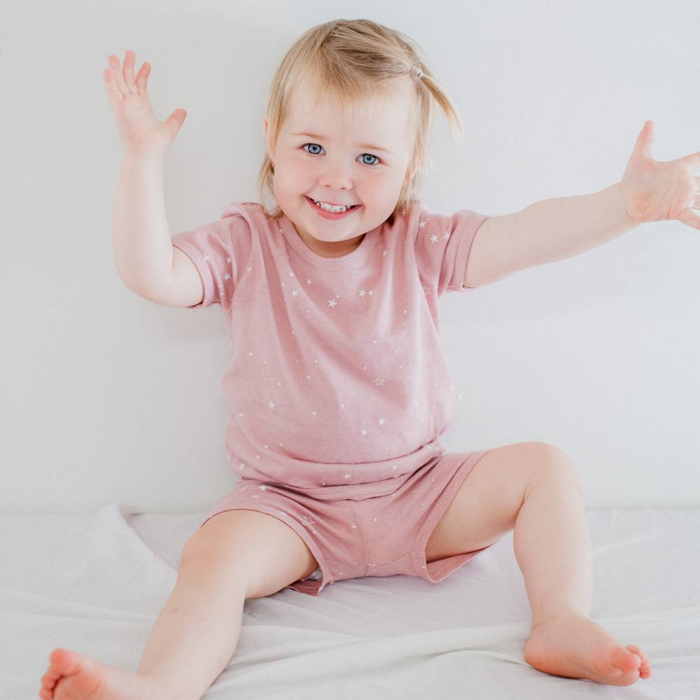 Child wearing a pink outfit with white polka dots on a light background