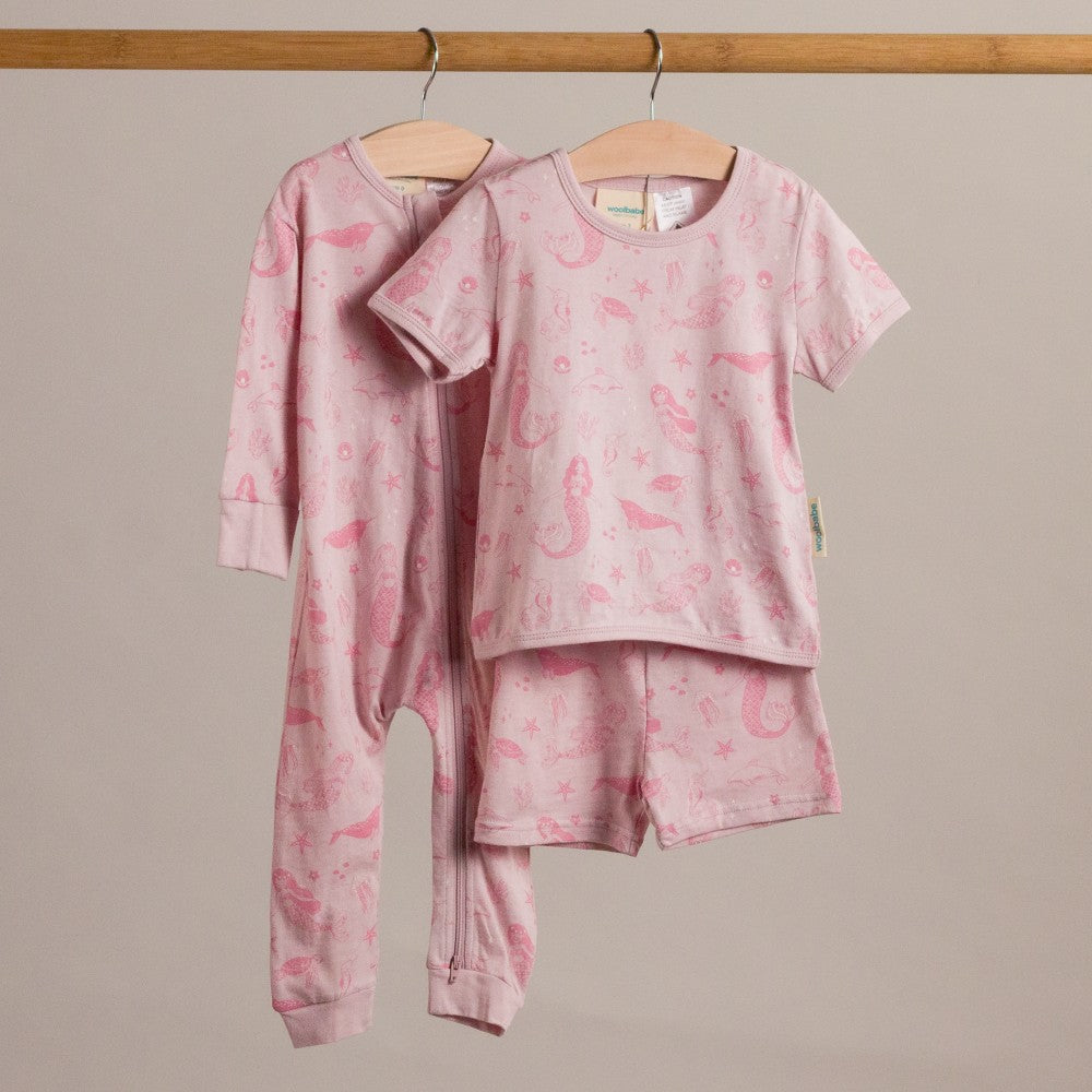Pink children's outfit with seahorse pattern on a beige background