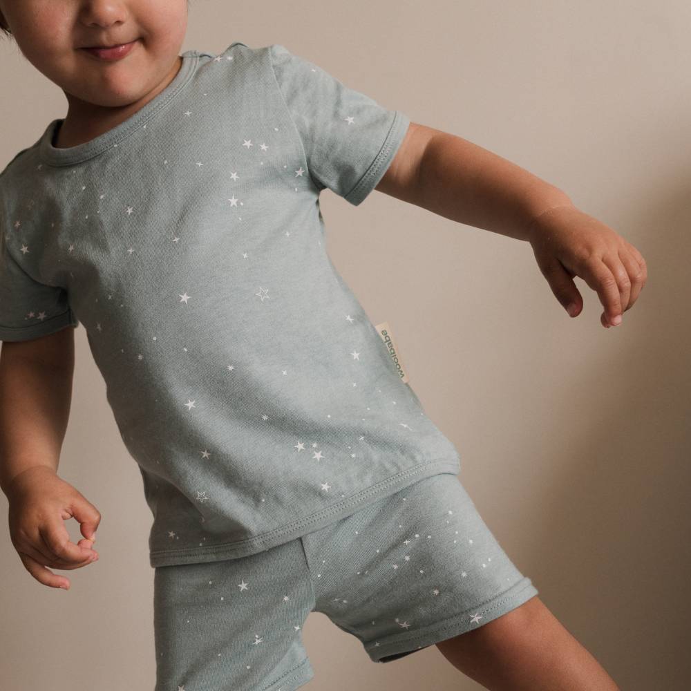 Child wearing a light blue pajama set with star patterns on a beige background