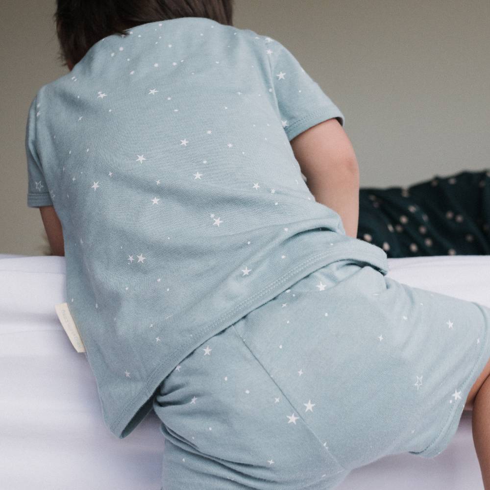 Child wearing a light blue pajama set with star patterns on a plain background