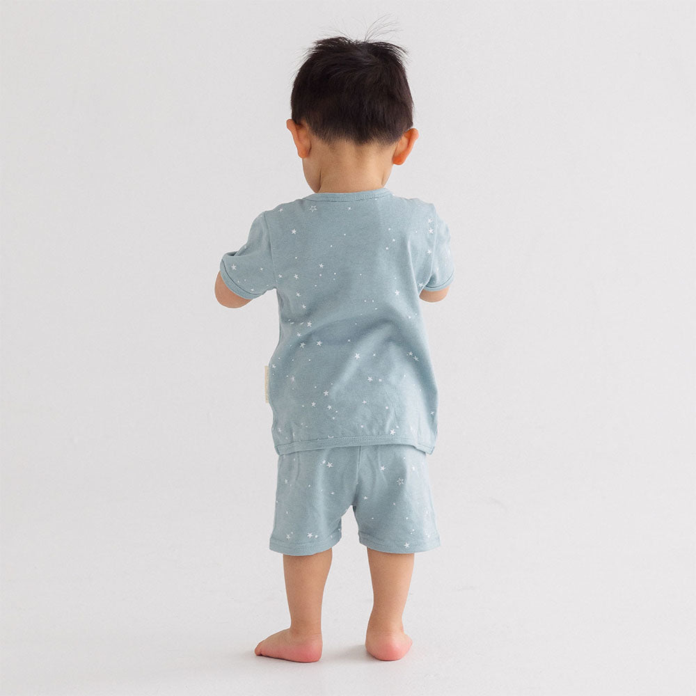 Child wearing a light blue pajama set with star pattern on a white background
