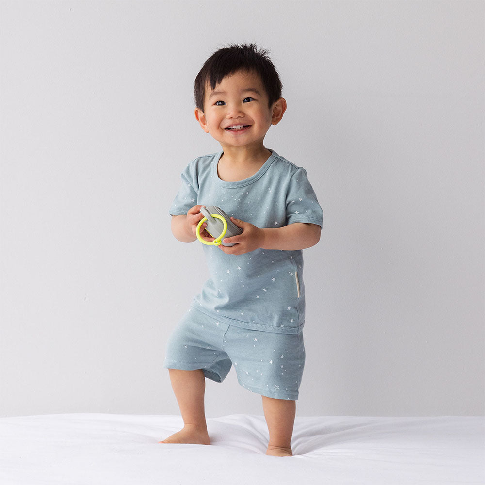 Child wearing a light blue outfit with star pattern, holding a toy, on a white background