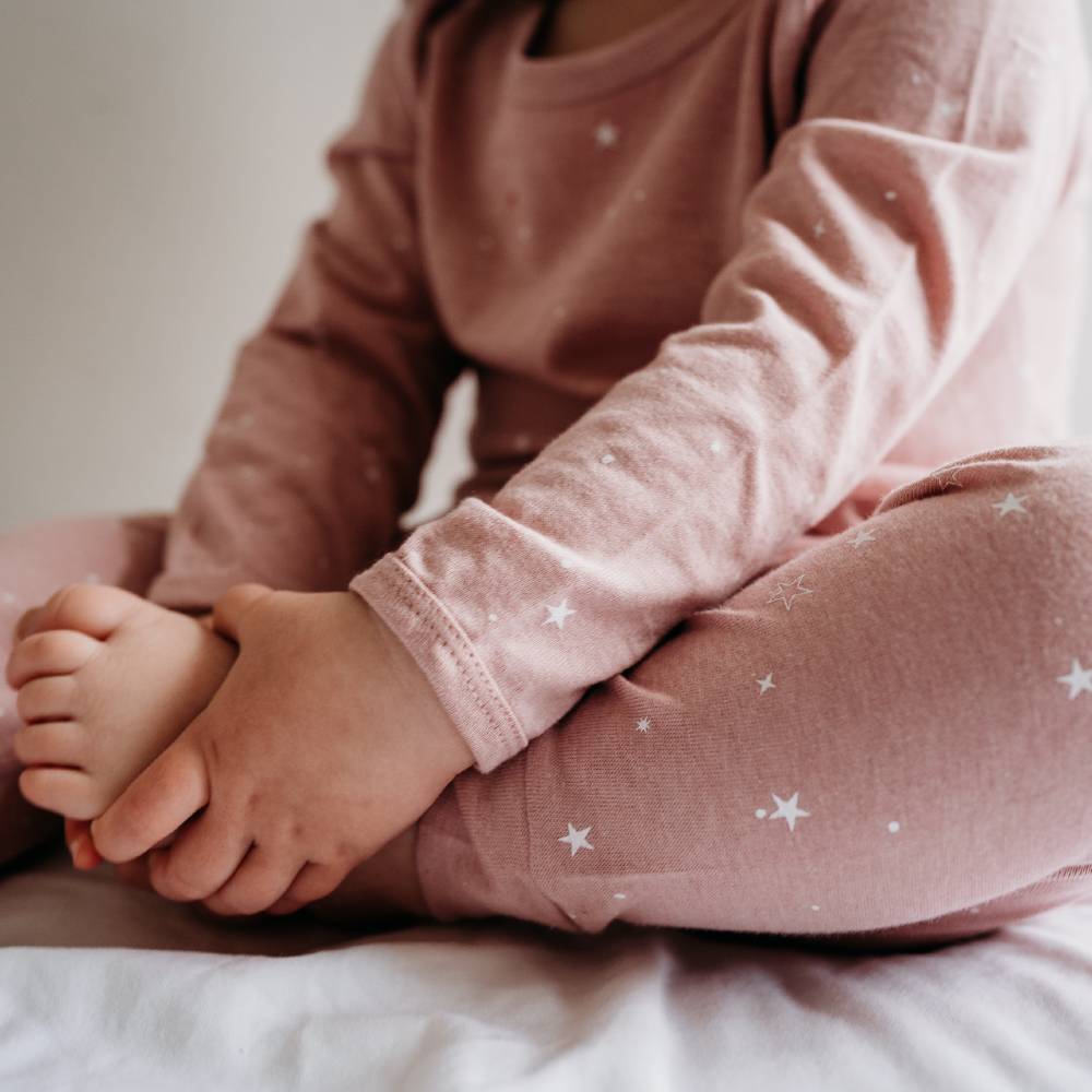 Child's feet in pink pajamas with star patterns on a light background