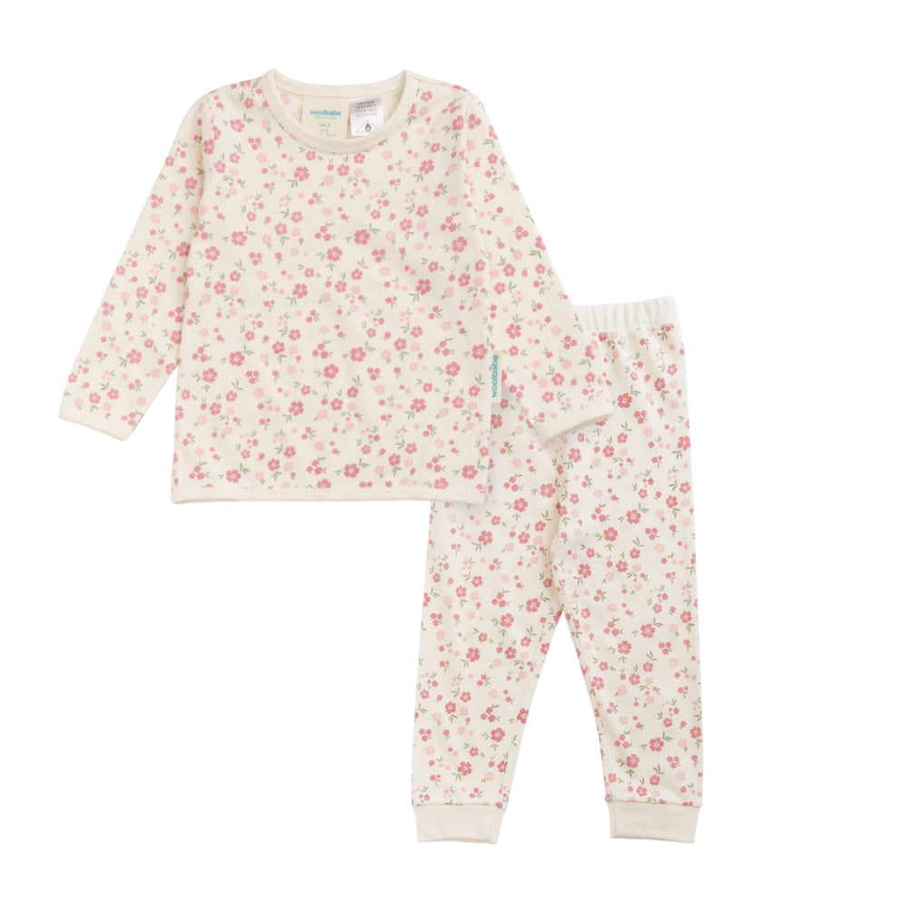 A two-piece children's pajama set featuring a long-sleeve top and matching pants in an off-white fabric with a dense pink and red floral print, laid flat on a white background.