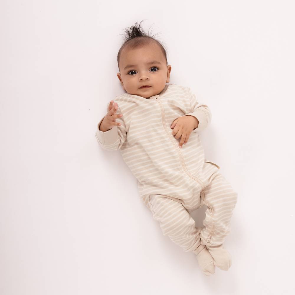 Baby wearing a ribbed beige onesie on a white background