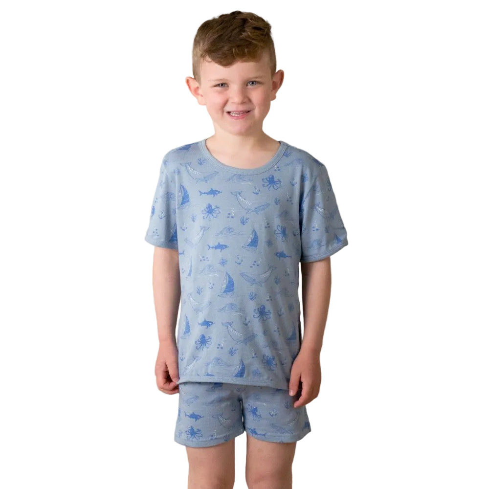 Child wearing a blue pajama set with animal prints against a plain background