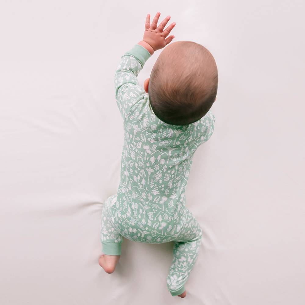 Baby wearing a green floral onesie on a white background