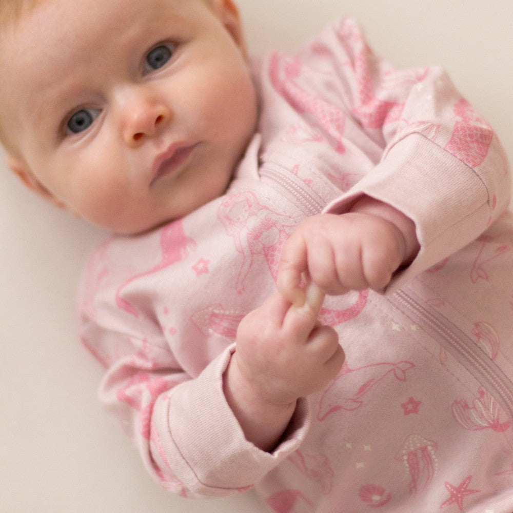 Baby wearing a pink outfit with patterns on a light background