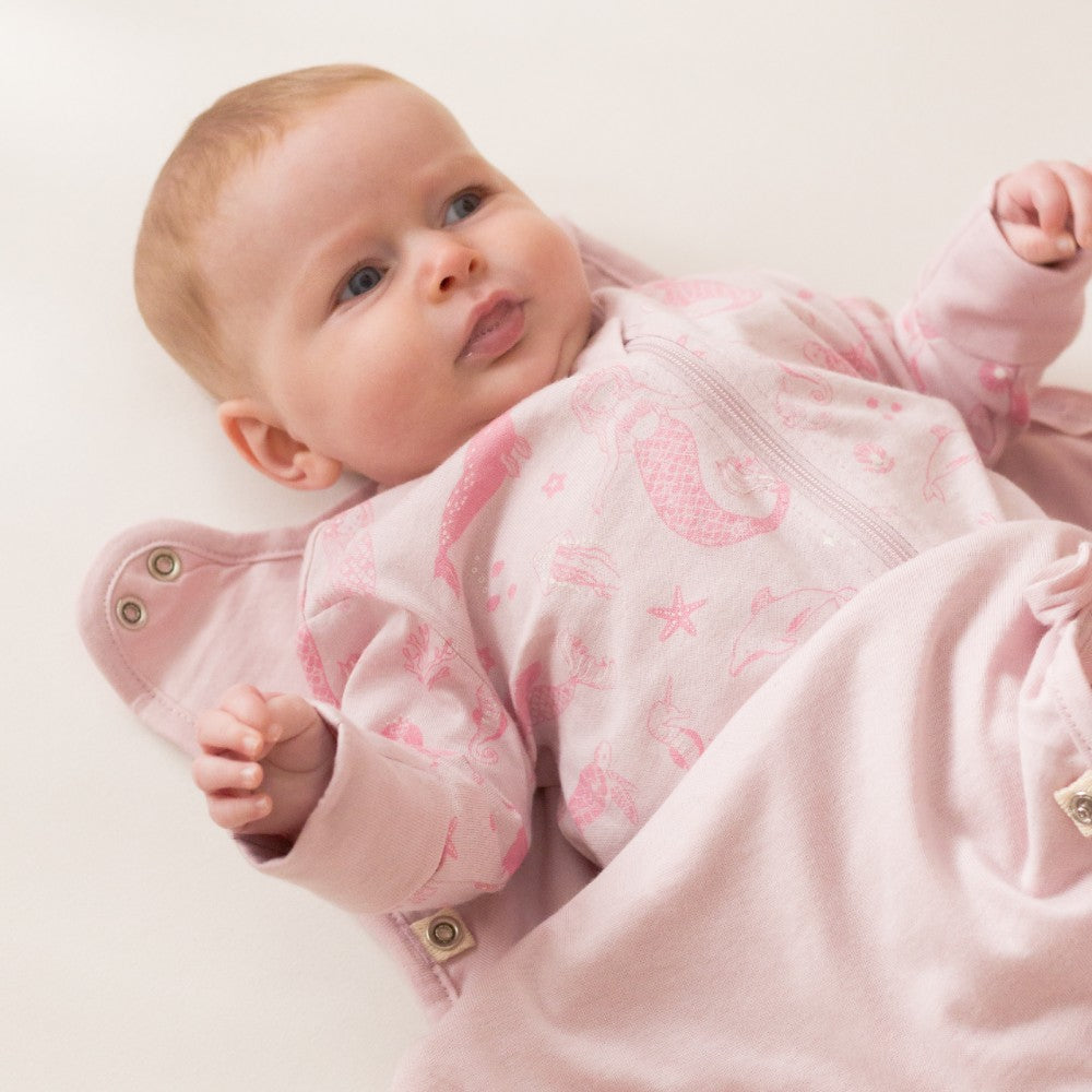 Baby in a pink outfit with star patterns on a light background
