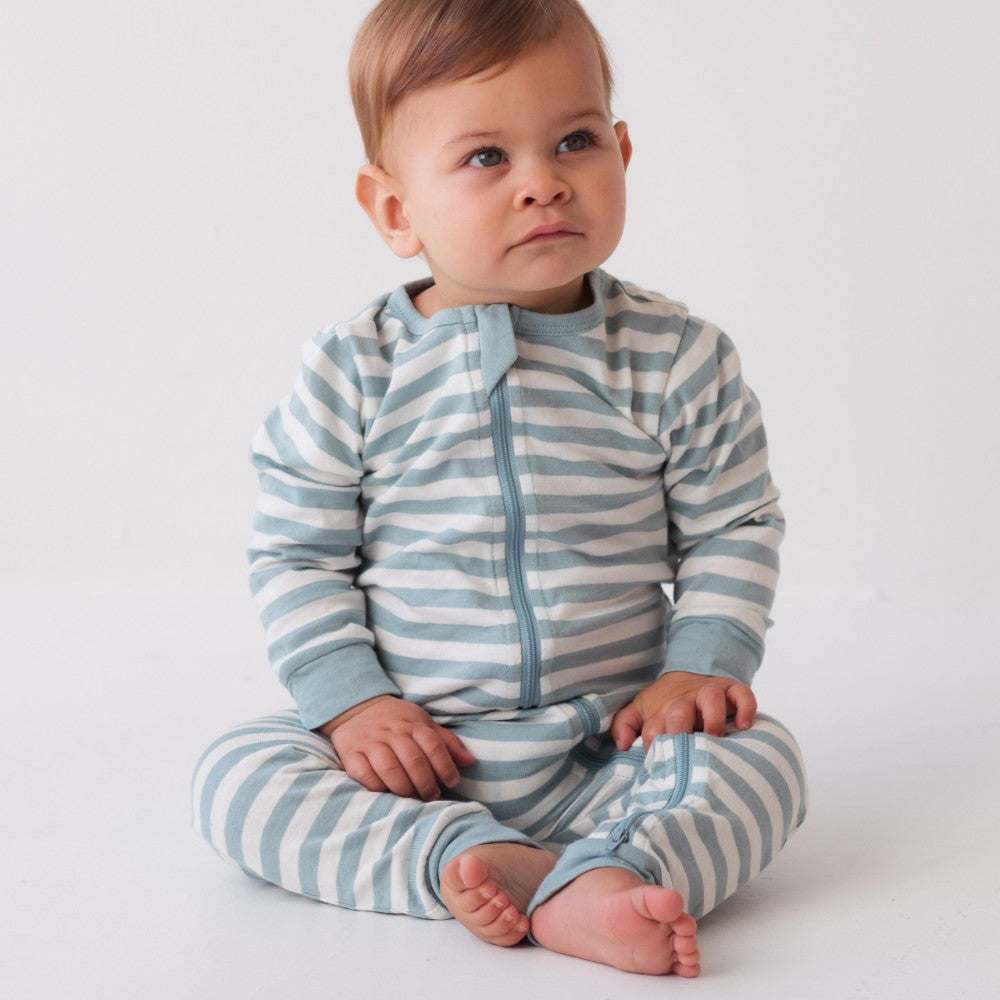 Baby wearing a blue and white striped onesie on a plain background