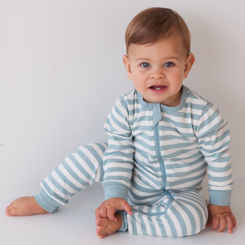 Baby wearing a blue and white striped woolbabe onesie on a plain background