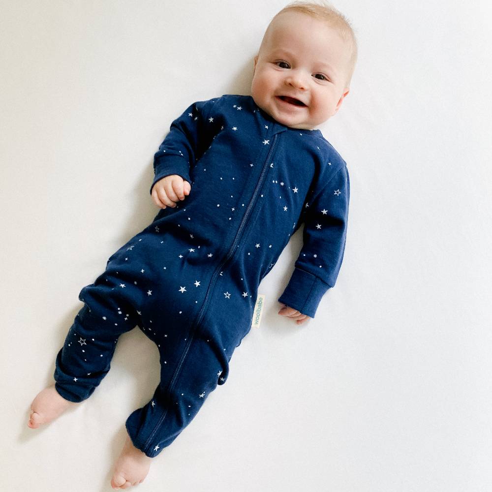 Baby wearing a navy blue onesie with star patterns on a light background