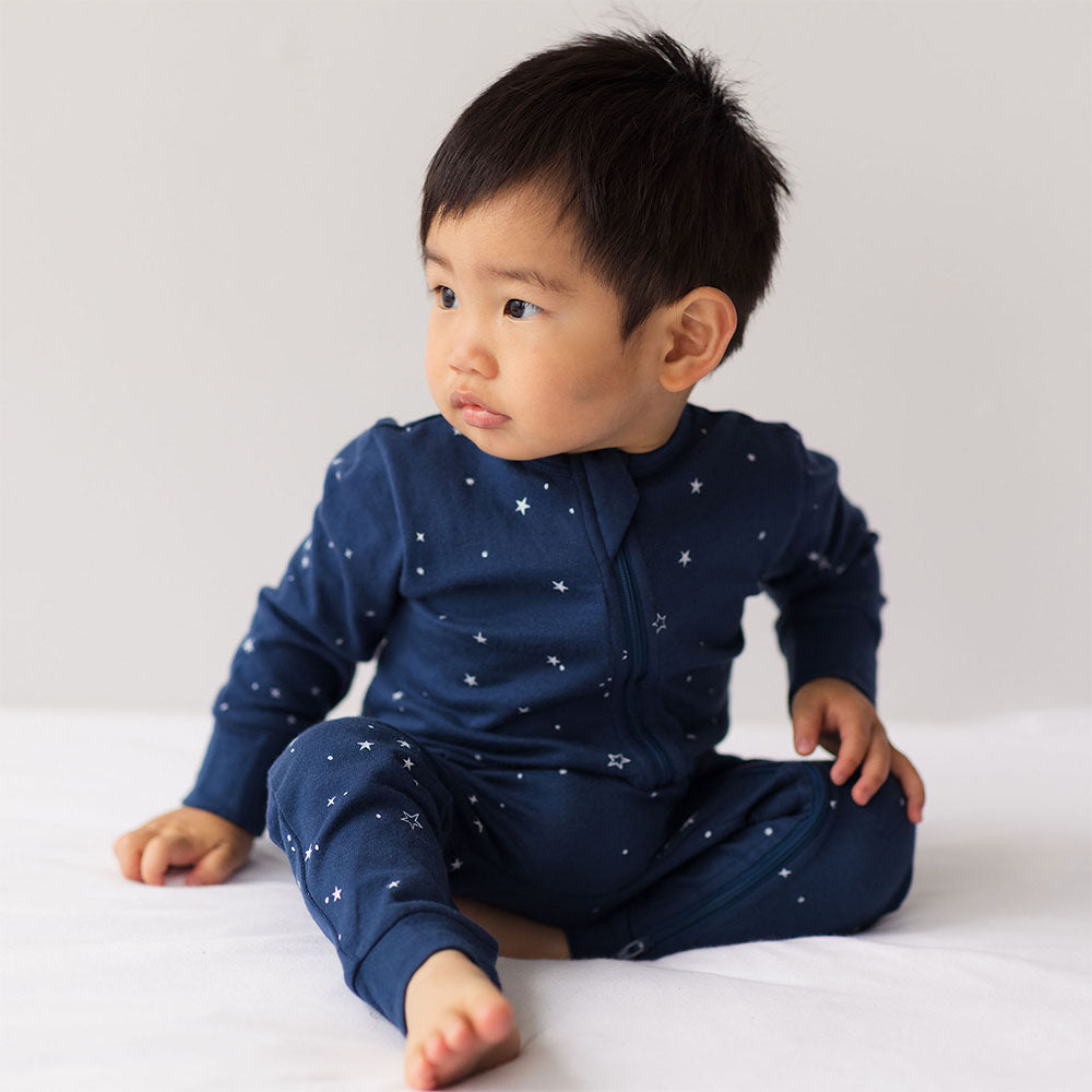 Baby wearing a navy blue outfit with star patterns on a white background