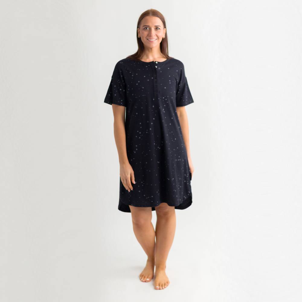 Woman wearing a navy blue nightshirt with small white patterns on a light gray background