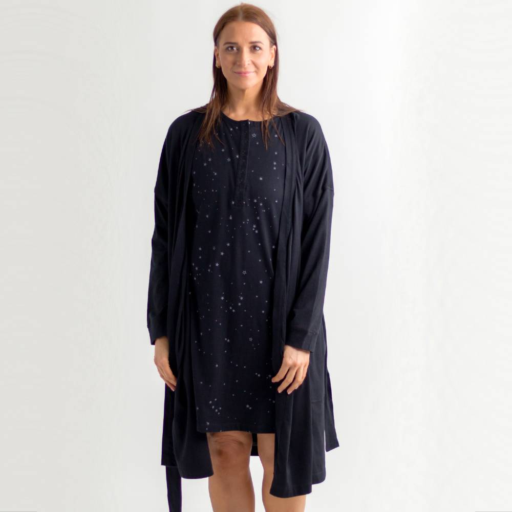 Woman wearing a black breastfeeding nightgown with star patterns and a matching merino robe on a white background