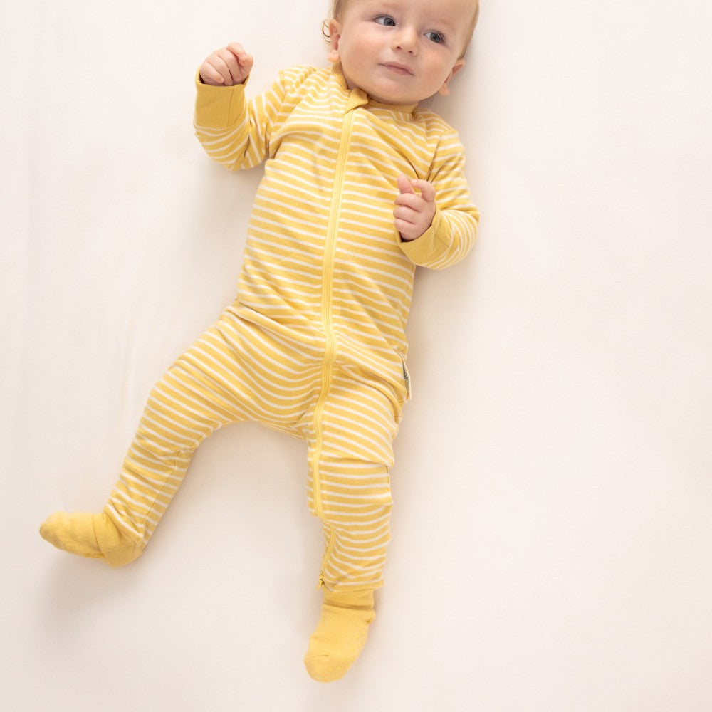 baby wearing yellow merino socks and singletsuit on white background