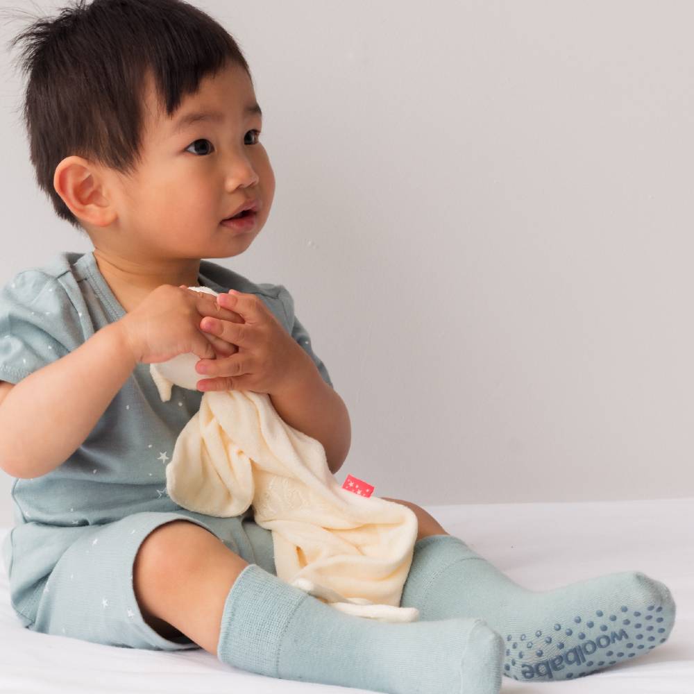 Child holding a baby blanket with a visible brand logo against a plain background