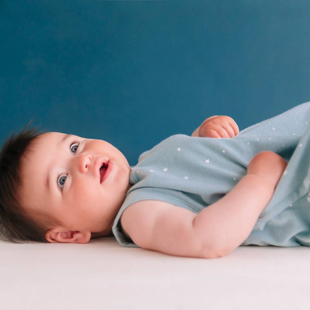 Baby lying on a white surface with a blue background