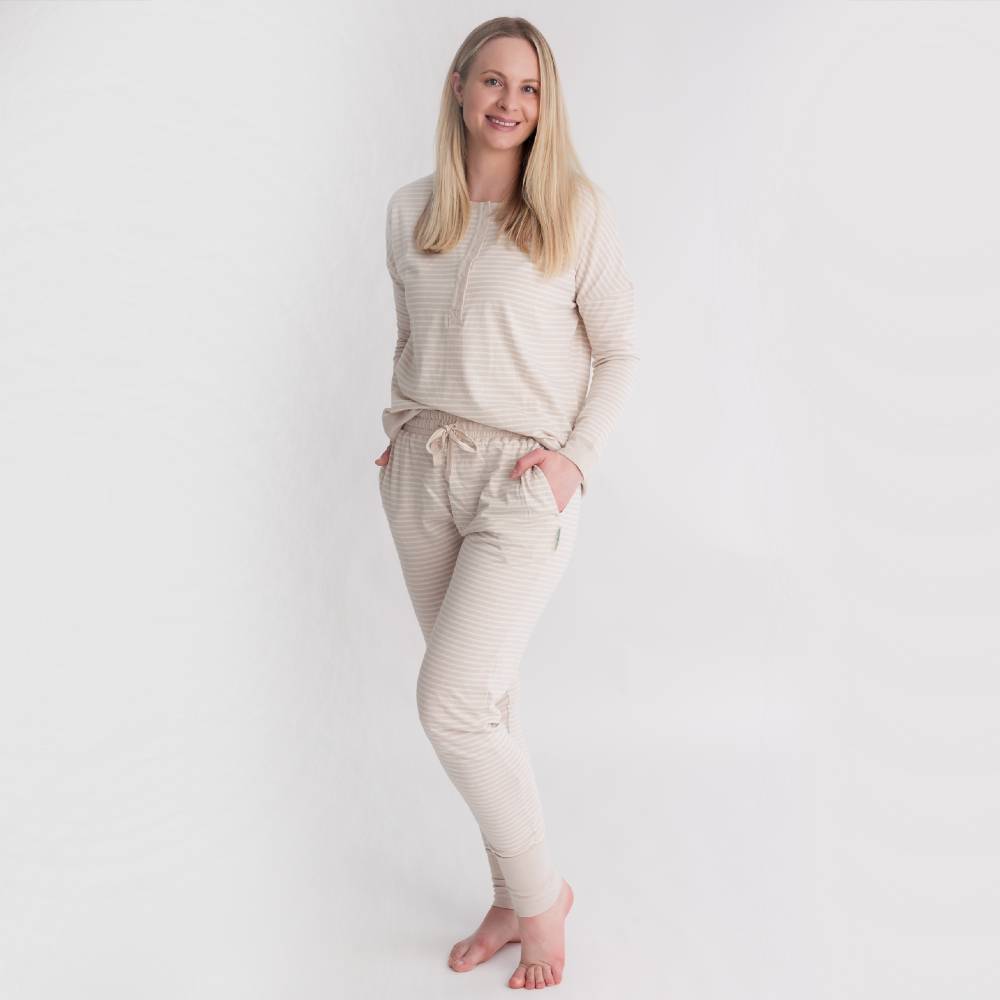 Woman wearing a beige and white striped pajama set on a plain background