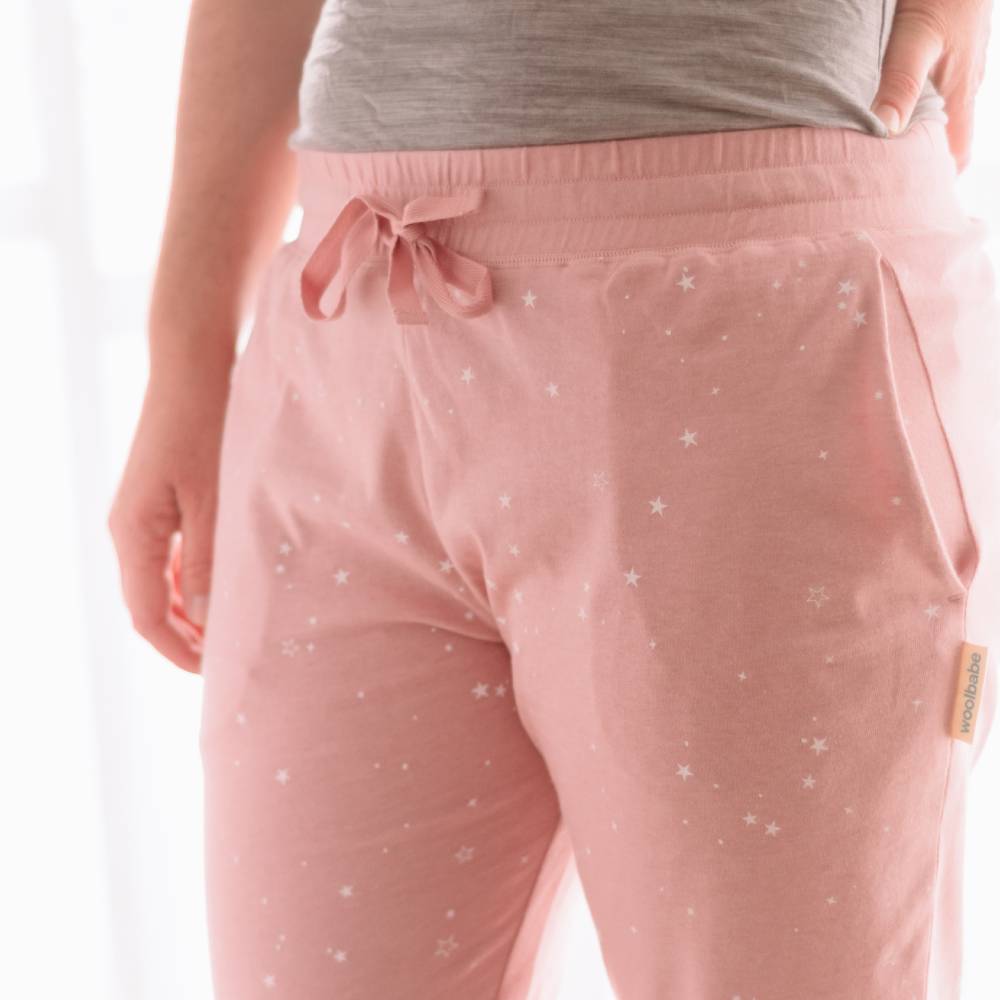 Pink drawstring pajama pants with star pattern worn by a person on a white background