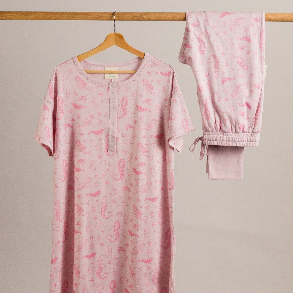 Pink pajama set with seahorse pattern on a hanger against a beige background