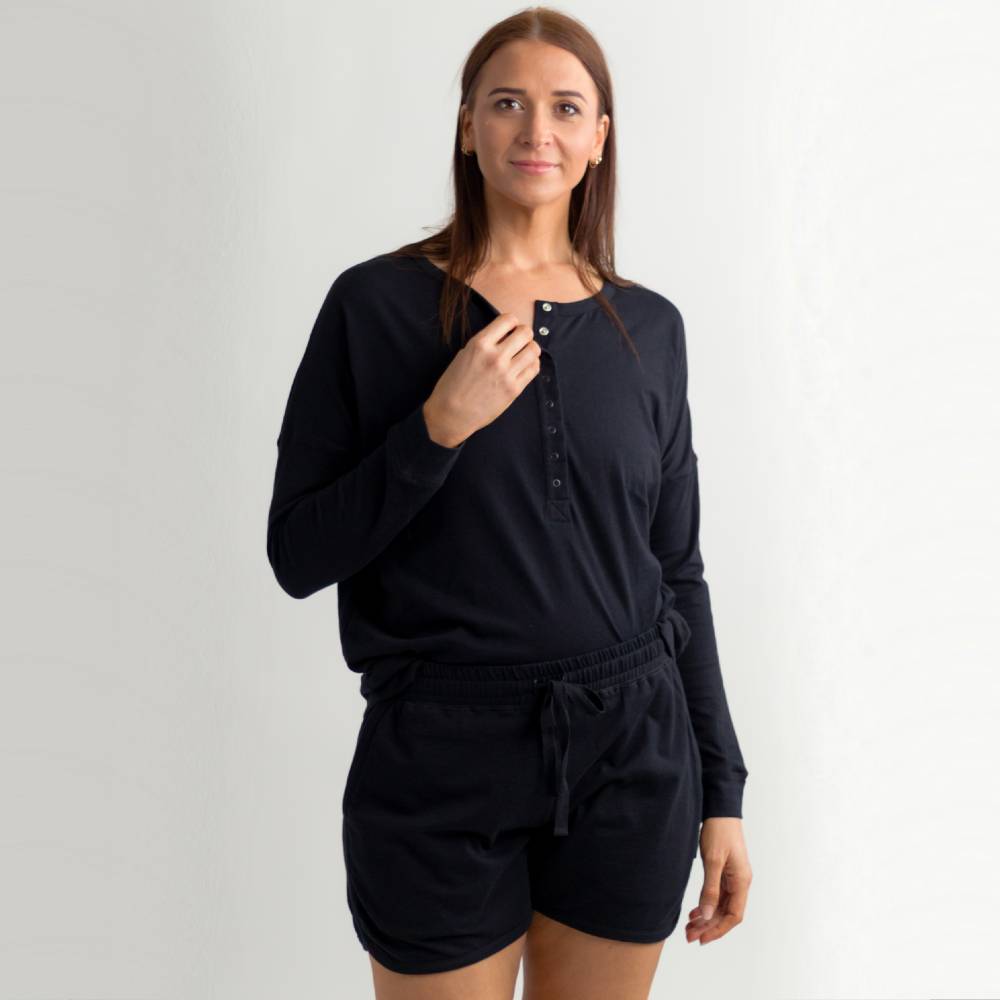 Woman wearing a black long-sleeve top and shorts set on a white background