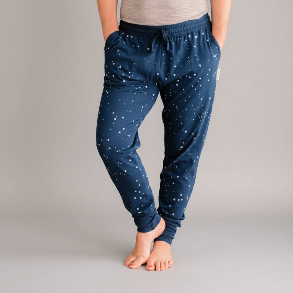Person wearing navy blue pajama pants with white star pattern on a wooden floor.