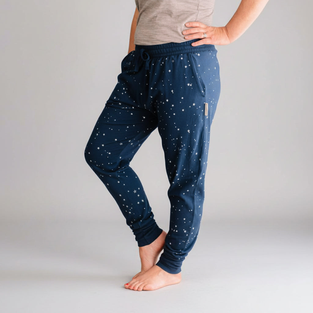 Person wearing navy blue pants with white patterns against a gray wall.