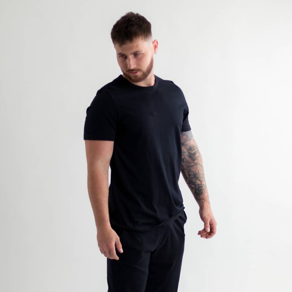 Man wearing a black t-shirt and pants on a white background
