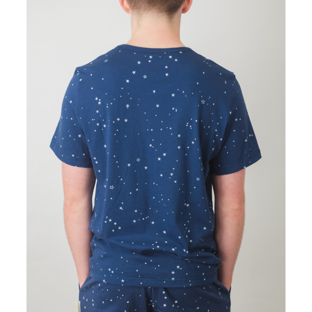 Person wearing a navy blue t-shirt with star pattern on a plain background
