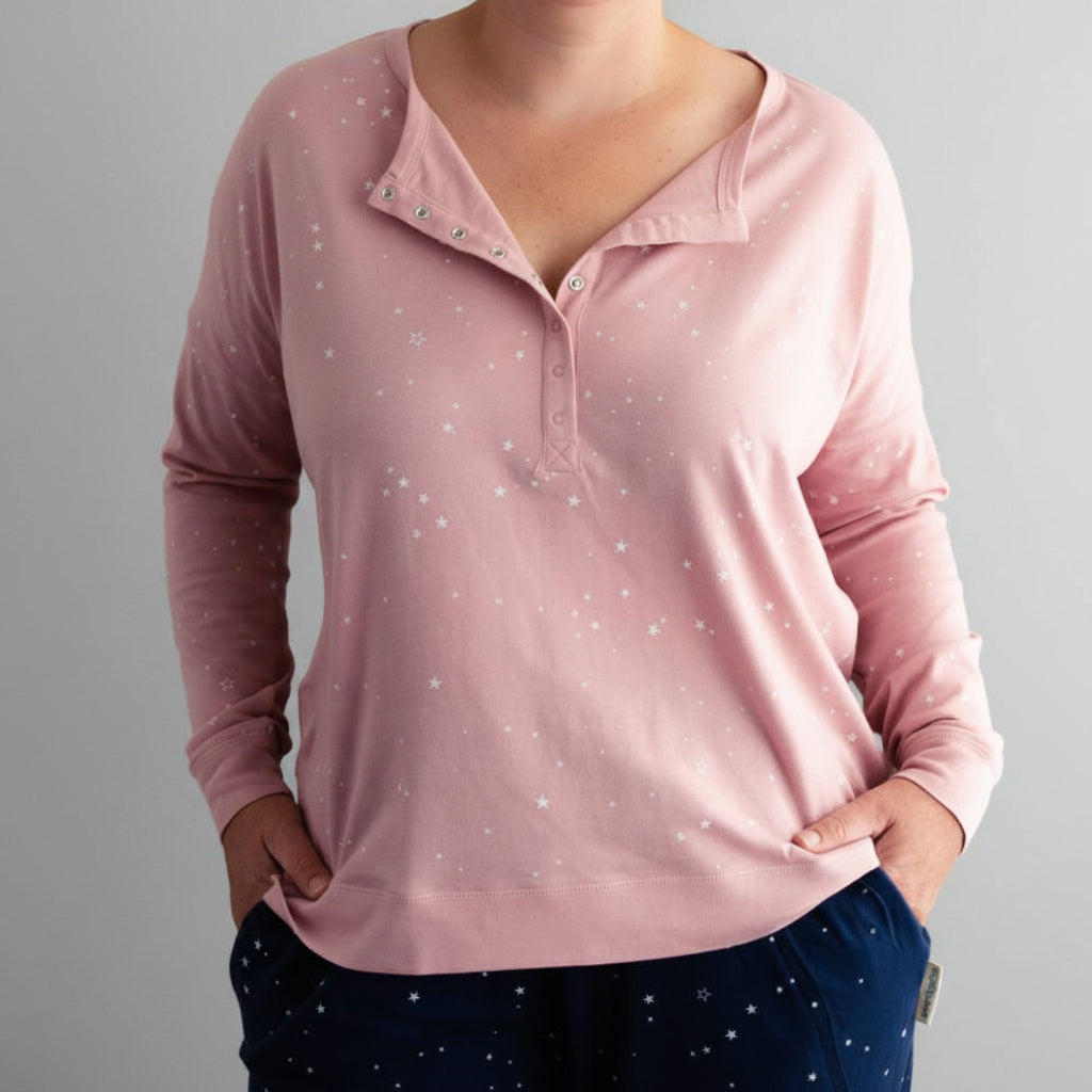 Pink long-sleeve lounge PJ  top with star pattern worn by a person against a dark background